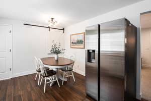 Dining area featuring a barn door and dark wood finished floors