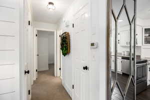 Hallway featuring ornamental molding and dark colored carpet