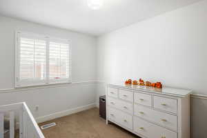 Unfurnished bedroom featuring light carpet and baseboards