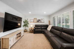 Living area with light colored carpet, ornamental molding, and recessed lighting