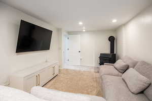 Living area featuring a wood stove, recessed lighting, and light colored carpet