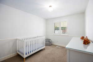Bedroom featuring light colored carpet and a crib