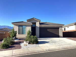 Prairie-style house featuring concrete driveway, stucco siding, an attached garage, and a tiled roof