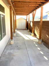 View of patio with a storage shed. Solar panels located on roof od patio cover.