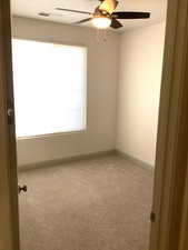 Guest bedroom with light colored carpet and a ceiling fan and white walls.