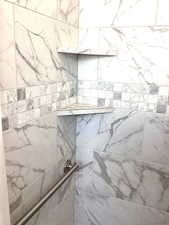 Primary Bathroom view of tiled shower and grab bars