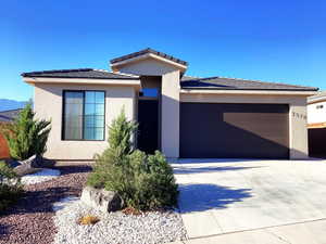 Prairie-style house with concrete driveway, a garage, stucco siding, and a tiled roof