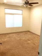 Primary bedroom with carpet floors and a ceiling fan, closet.  Walls are white.