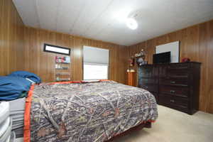 Bedroom featuring wood walls and light carpet