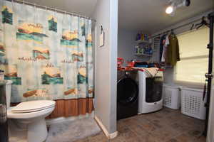 Full bathroom featuring separate washer and dryer and stone finish flooring