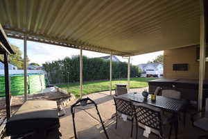 View of patio / terrace featuring a hot tub, outdoor dining space, and a grill