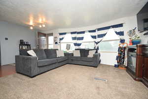 Carpeted living room featuring a textured ceiling
