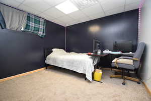 Bedroom with a paneled ceiling and light carpet