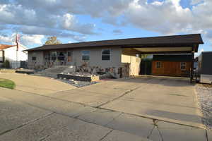 View of front of home with driveway, a shed, and roof with shingles
