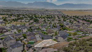 Aerial view of property and surrounding area with a mountainous background, property parcel outlined, and nearby suburban area