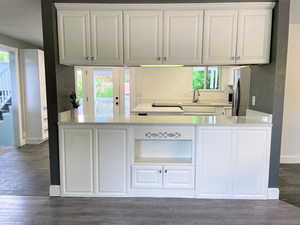 Kitchen featuring white cabinetry, light stone countertops, dark wood-type flooring, and healthy amount of natural light