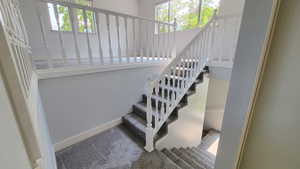 Staircase with healthy amount of natural light and carpet floors