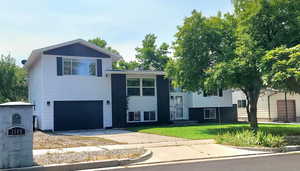 Split foyer home featuring driveway, a front lawn, and a garage