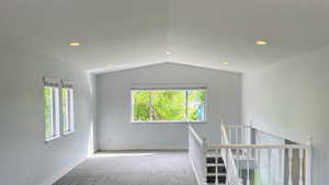 Unfurnished room featuring carpet flooring, plenty of natural light, recessed lighting, and lofted ceiling