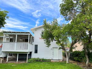 Back of house with a wooden deck and a lawn