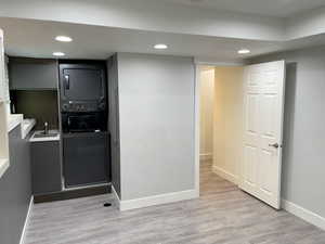 Laundry area featuring recessed lighting, light wood-style flooring, and estacked washer and dryer