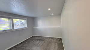 Unfurnished room featuring dark carpet, a textured ceiling, and recessed lighting