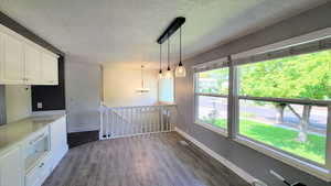 Unfurnished dining area with dark wood finished floors, a chandelier, and a textured ceiling