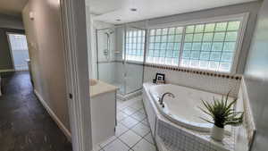 Bathroom featuring a garden tub, a stall shower, vanity, and tile patterned flooring