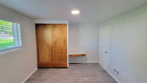 Unfurnished bedroom with light wood-style floors and a closet