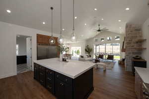 Kitchen featuring decorative light fixtures, high vaulted ceiling, a center island, built in refrigerator double wide fridge and freezer.