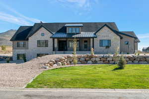 View of front facade featuring covered porch, a front yard, board and batten siding, a standing seam roof, and a metal roof