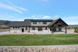 Rear view of property featuring board and batten siding, a mountain view, a lawn, and a patio area