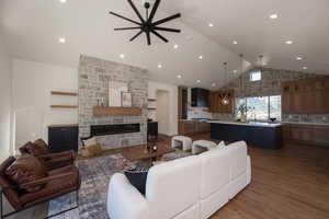 Living area with a fireplace, dark wood-style floors, high vaulted ceiling, a ceiling fan, and recessed lighting