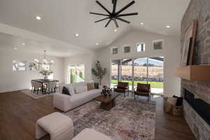 Living area with high vaulted ceiling, dark wood-style flooring, recessed lighting, ceiling fan, and a fireplace