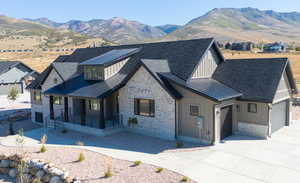 View of front of home with board and batten siding, covered porch, a mountain view, and stone siding