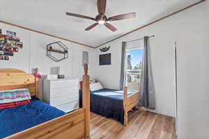 Second bedroom featuring crown molding, light wood finished floors, a textured ceiling, and ceiling fan