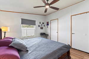 Primary bedroom featuring ornamental molding, a textured ceiling, wood finished floors, and ceiling fan