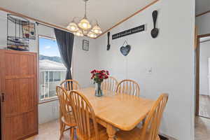 Dining room featuring ornamental molding, a textured ceiling, and a chandelier