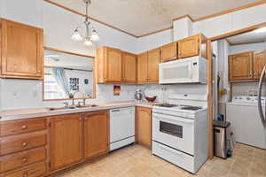 Kitchen featuring a textured ceiling, white appliances, ornamental molding, pendant lighting, and washer / clothes dryer