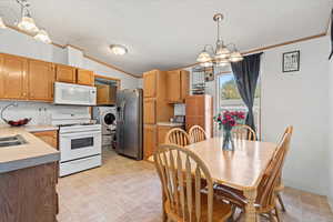Dining space with ornamental molding, a chandelier, lofted ceiling, a textured ceiling, and light floors