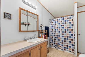 Primary bathroom with a textured ceiling, vanity, and light floors