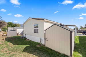 View of property exterior featuring a lawn and a storage shed