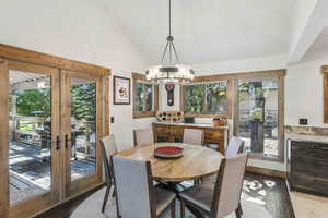 Dining space featuring french doors, a chandelier, and high vaulted ceiling