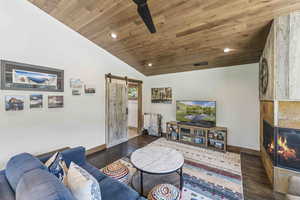 Living room featuring a barn door, recessed lighting, wooden ceiling, dark wood-style flooring, and lofted ceiling