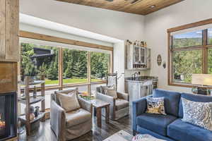 Living room featuring dark wood finished floors, plenty of natural light, wooden ceiling, and a high end fireplace