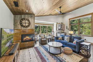 Living room with a fireplace, lofted ceiling, wooden ceiling, hardwood / wood-style flooring, and a ceiling fan