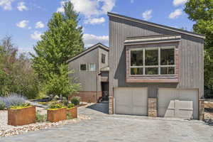 View of front of house with stone siding and decorative driveway