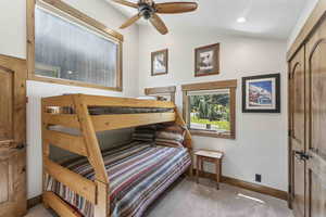 Bedroom with light colored carpet, ceiling fan, and lofted ceiling