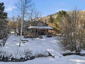 Snow covered rear of property with a gazebo and a deck