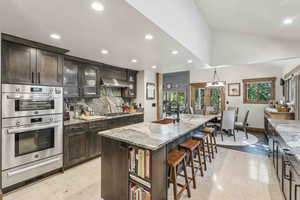 Kitchen featuring glass insert cabinets, recessed lighting, appliances with stainless steel finishes, backsplash, and light stone countertops